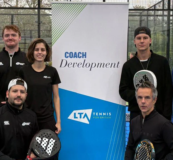 Five people beside a coach development banner at a padel court